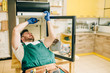 © Nomad_Soul - Worker in gloves repair refrigerator at home
