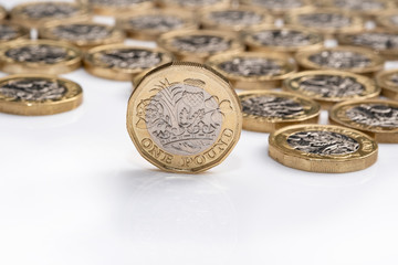 Wall Mural - UK money, picture shows pound coin standing on edge with background of coins 