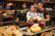© estradaanton - Young man and woman stand at cheese shelf in grocery store. Happy positive workers pose on camera and smile. Cheese paradise.