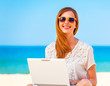 © Masson - Cute woman with white laptop on the summer beach