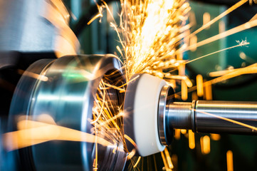 End processing of a metal surface with an abrasive stone on a circular grinding machine, sparks fly in different directions.