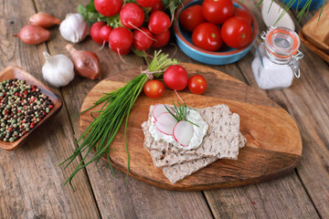 Wall Mural - crispbread with quark and fresh chive, radish and tomatoes on a rustic wooden table - healthy breakfast with fresh herbs   - top view