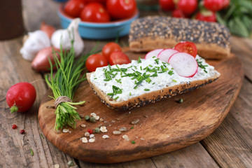 Wall Mural - healthy breakfast -  wholemeal roll with quark and fresh chives, radishes and tomato on a rustic wooden table - healthy breakfast