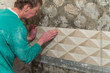 The worker puts tiles on the wall. Finishing works, blurred focus. The technology of laying tile.