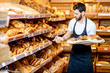 © rh2010 - Handsome baker in uniform putting fresh pastries on the shelves in the supermarket