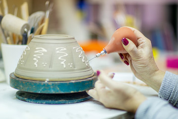 Clay pot in making proces by pottery artist with woman hands on  plan