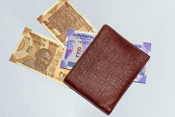 Close up view of wallet with brand new Indian 10, and 100 rupees banknotes on white isolated background and copy space.