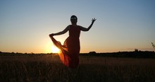 Inspired Woman In A Red Dress Dancing In A Horizonless Field At Sunset
