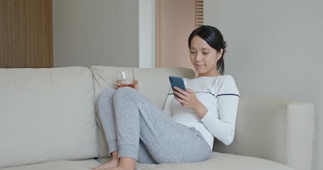 Wall Mural - Woman look at cellphone with cup of tea, relax at home