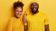 © WHstudio Leushin N - Photo of cheerful dark skinned young lady and man stand closely, enjoy spare time, listens funny news from interlocutor, wear spectacles and yellow clothes. People, emotions, ethnicity concept