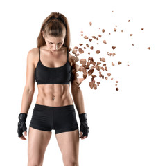 young fit woman in gym clothes looking down, one arm practically dissolved in particles, isolated on