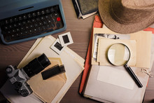 Investigator Desk With Confidential Documents, Camera, Magnifying Glass, Vintage Typewriter And Hat. Secret Documents Investigation Concept.