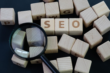 Wall Mural - SEO, Search Engine Optimization top ranking in search result page concept, magnifying glass with wooden cube block with alphabet building the word SEO on blackboard background