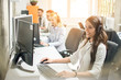 © Bojan - Friendly smiling customer support operator woman talking with client using headset and computer in call center.