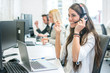 © Bojan - Cheerful young business woman with headphones talking with client in call center. Smiling female customer support operator working in office
