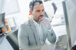 © Bojan - Pensive or confused business man working on computer in bright office