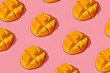 Colorful fruit pattern of fresh juicy cutted mango on coral pink background, top view