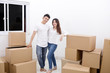 © Creativa Images - Happy couple standing with a stack of cardboards