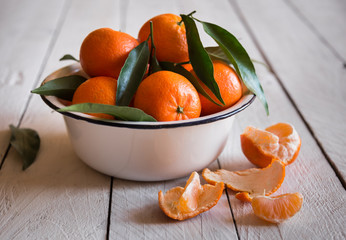 Ripe delicious mandarines with zest on white wooden table