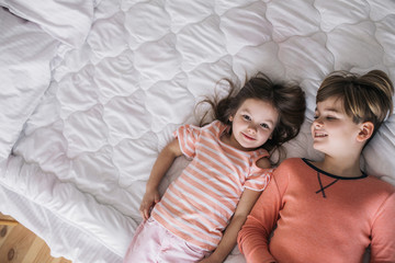 Top view of happy children lying on bed in granny's house