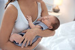 © New Africa - Young woman holding her baby near breast in bedroom, closeup