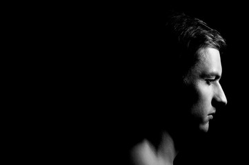 Dramatic portrait of a guy on a black background, black and white photography