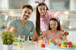 © New Africa - Father, mother and daughter painting Easter eggs in kitchen