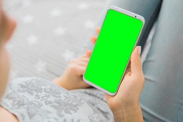 Wall Mural - Green screen smartphone. key image of woman's hands close up. holding mobile phone. Mockup chroma