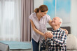 Elderly man with cup of tea near female caregiver at home. Space for text