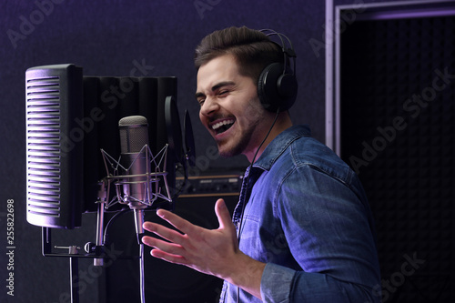 Fotografía Young singer with microphone recording song in studio