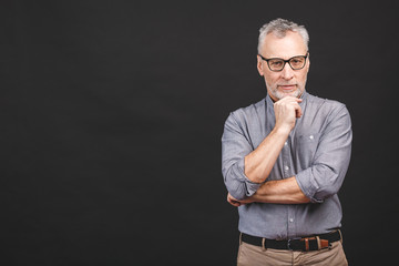 Wall Mural - Portrait of a mature businessman wearing glasses isolated against black background. Happy senior man looking at camera with copy space. Close up face of happy successful business man.