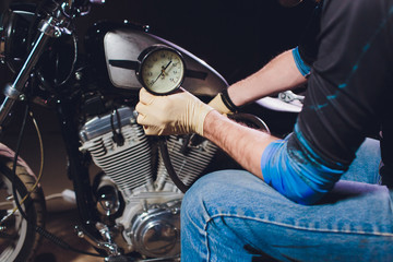 Man fixing bike. Confident young man repairing motorcycle near his garage. barometer