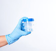 © nndanko - hand in a blue sterile glove holds a plastic container for collecting analyzes