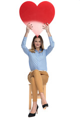 Sticker - happy businesswoman holds red heart shape in the air