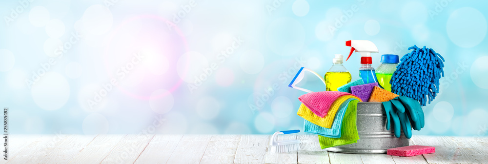 Bucket Of Cleaning Supplies On Wooden Table With Clean Blue Bubbly Background - Cleaning Services Concept - obrazy, fototapety, plakaty 