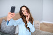 © BestForYou - Beautiful smiling woman with a phone takes a selfie at home.
