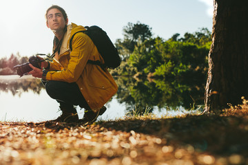 Wall Mural - Tourist sitting near a lake with a dslr camera