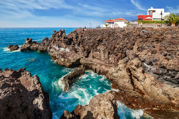 View of the shore with volcanic rocks in a small town Playa San Juan on the southern coast of Tenerife. Canary Islands., Spain.