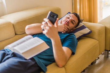 Man looking at his phone, procrastinating, avoiding obligations