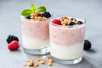 Wall Mural - Yogurt with berries raspberry, blueberry and blackberry, crunchy granola and mint leaf in jar on concrete background. Closeup view. Healthy eating, healthy food and vegetarian vegan diet concept