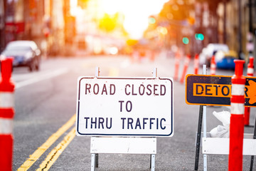 Road closed and detour sign in a road construction site work zone in the middle of a blocked street and traffic