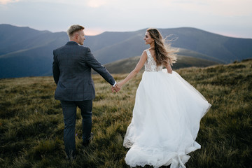 Beautiful wedding couple, bride and groom, in love on the background of mountains