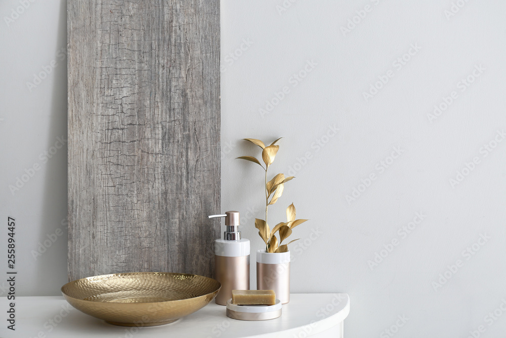 Golden bowl with water and cosmetics on table in bathroom