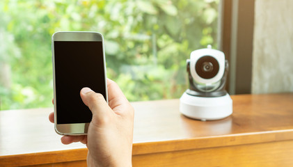 Smartphone connecting with security IP camera on a wooden table.