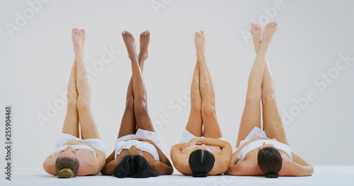 Portrait of beautiful young women of different ethnicities with perfect firm and slim bodies with hairless soft and silky legs crossed isolated on a white background Tableau sur Toile