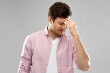 mind, health problem and stress concept - unhappy indian man suffering from headache over grey backg