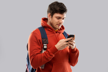 education, travel and technology concept - young man or student with smartphone and school bag or backpack over grey background