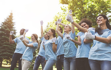 Group of happy volunteers celebrating success up in park