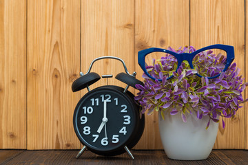 Little tree in white vase with vintage alarm clock on wooden table