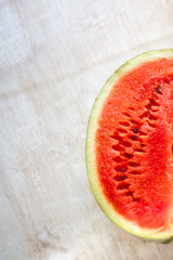 Sticker - Half a juicy watermelon on a light white wooden background, close-up. View from above